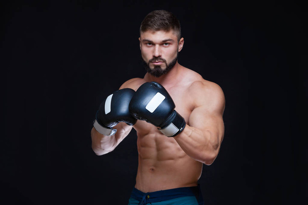 Strong muscular boxer in black boxing gloves. Isolated on black background. - Фото, зображення