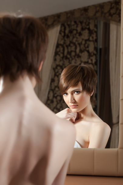 Reflection of attractive young brunette in mirror - 写真・画像