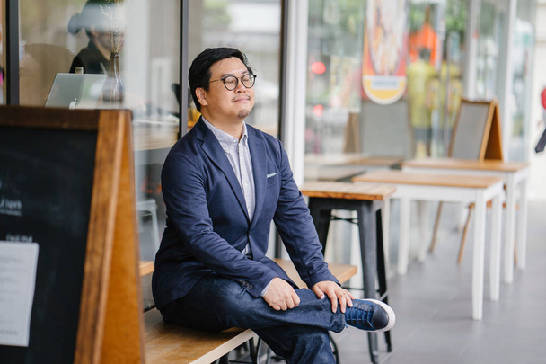 Portrait of a middle-aged Chinese Asian man in a casual suit (button-down oxford shirt, jacket ). He is wearing glasses and looking stylish, smart, educated and confident. - 写真・画像