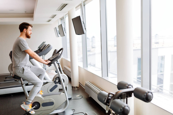 Man cardio training on a bicycle in a gym - Zdjęcie, obraz