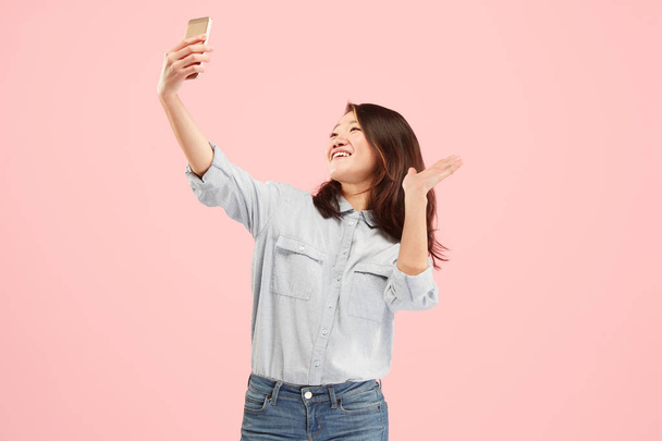 Portrait d'une fille décontractée souriante heureuse montrant écran vierge téléphone mobile isolé sur fond rose
 - Photo, image