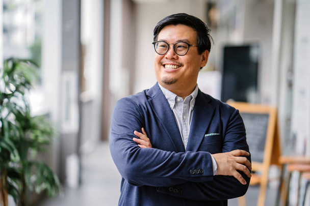 Portrait of a middle-aged Chinese Asian man in a casual suit (button-down oxford shirt, jacket ). He is wearing glasses and looking stylish, smart, educated and confident. - Foto, immagini