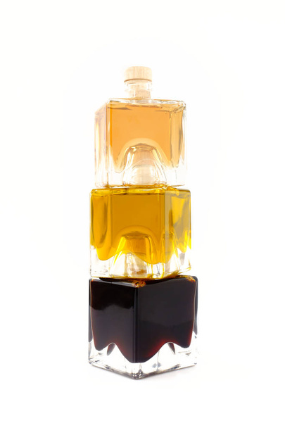 Stapel von Balsamico Bianco, Balsamico-Essig aus Modena und extra vergine Olivenölglasflaschen auf weißem Hintergrund. - Foto, Bild