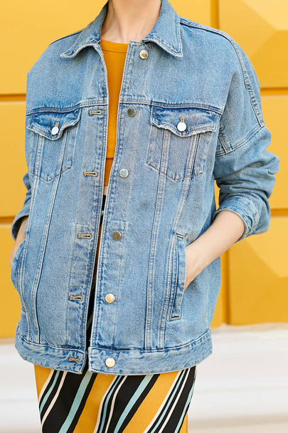 Stijlvolle, vrouwelijke look uit een jean jas, gele top en rok. Streetstyle. - Foto, afbeelding