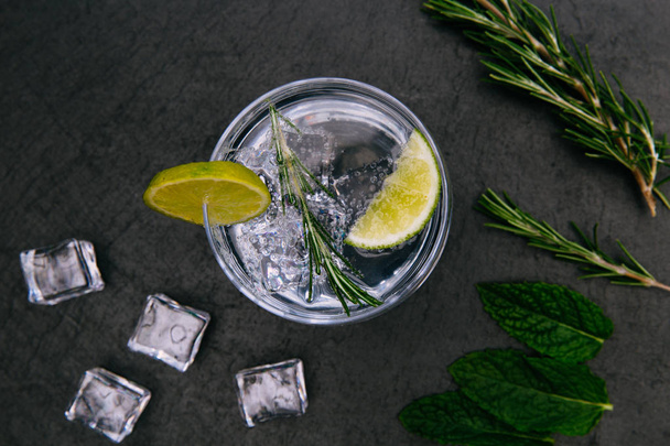 gin tonic cocktail drankje met ijs glas op donkere achtergrond - Foto, afbeelding