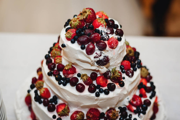甘いイチゴ、さくらんぼ、ブルーベリー、黒スグリとホワイト クリームのウェディング ケーキ - 写真・画像