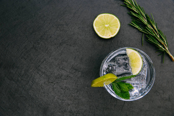 Gin Tonic Cocktailgetränk mit Eisglas grüne Limette auf dunklem Hintergrund - Foto, Bild