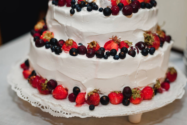 білий вершковий весільний торт зі свіжою полуницею, вишнями, чорницею, чорною смородиною
 - Фото, зображення