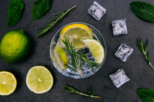 Gin tonic cocktail boisson avec verre à glace vert citron vert sur fond sombre
 - Photo, image