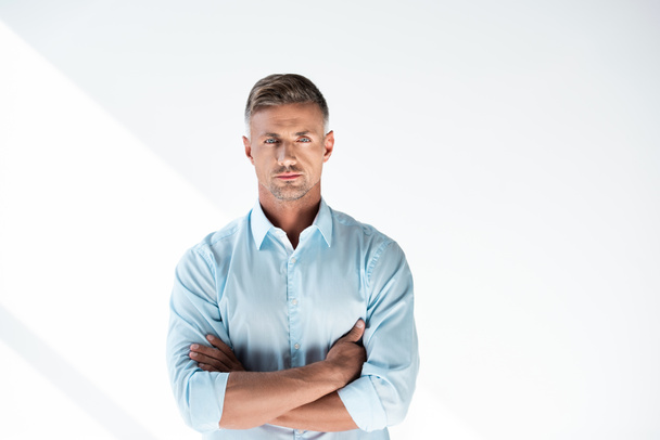 hombre adulto serio en camisa mirando a la cámara con los brazos cruzados aislados en blanco
 - Foto, Imagen