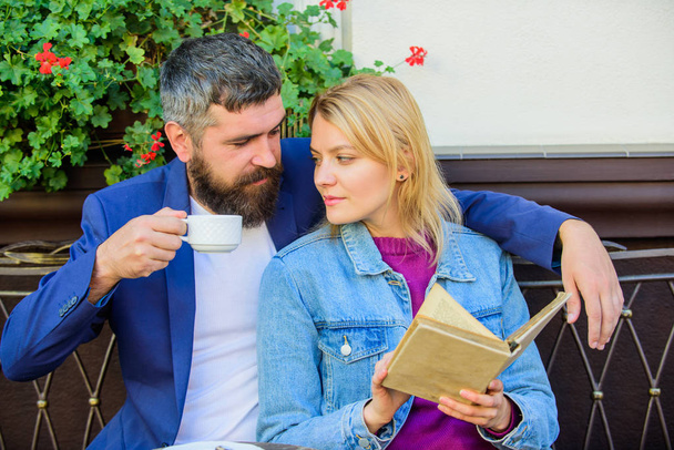 Love and flirt. Common interests. Couple in love sit cafe terrace. Man with beard and blonde woman cuddle on romantic date. Romance concept. Couple flirting romantic date read book. Romantic date - Foto, Bild