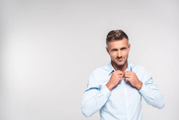 handsome adult man buttoning shirt isolated on white - Zdjęcie, obraz