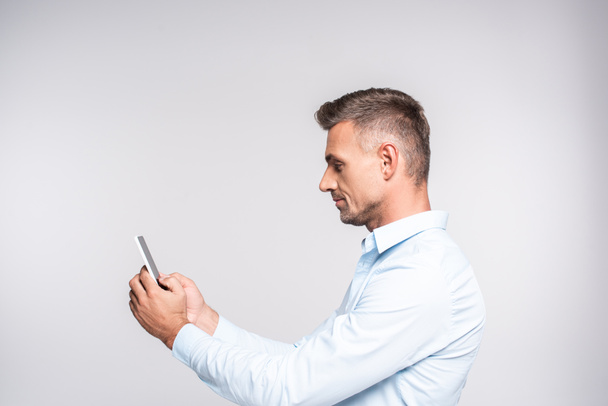 вид збоку красивого дорослого чоловіка за допомогою смартфона ізольовано на білому
 - Фото, зображення