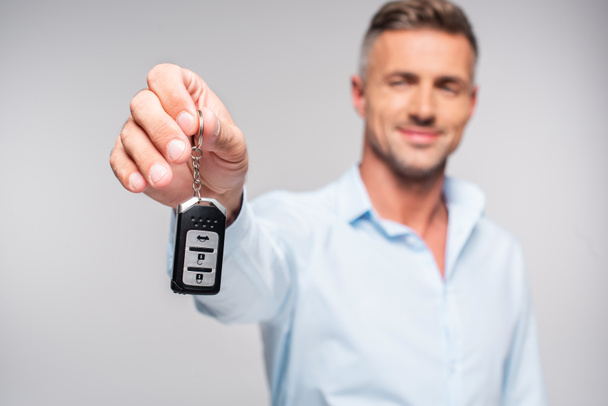 close-up shot of smiling adult man holding car alarm remote isolated on white - 写真・画像