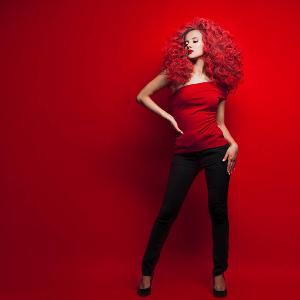 Portrait of beautiful young woman with red hair on red background - 写真・画像