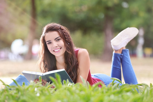 Jeune femme au repos avec livre dans le parc
 - Photo, image