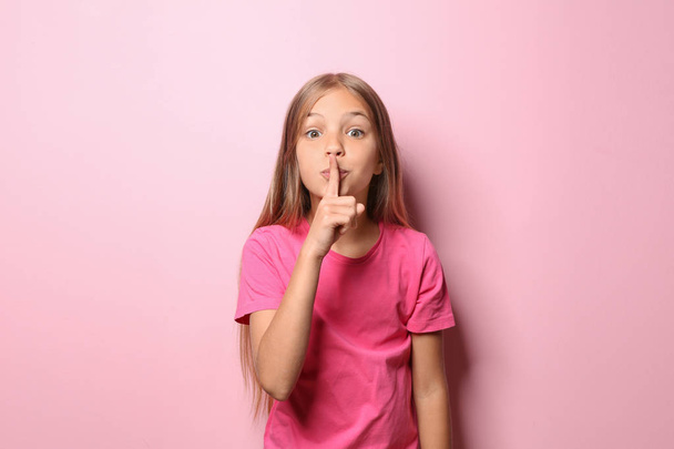 Κοριτσάκι σε χειρονομία σιωπή δείχνει t-shirt σε χρώμα φόντου - Φωτογραφία, εικόνα