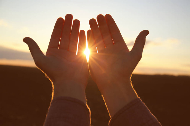 Ręce człowieka religijnego, modląc się na zewnątrz o zachodzie słońca - Zdjęcie, obraz