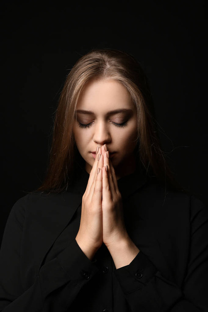 Beautiful young woman praying on dark background - Fotografie, Obrázek