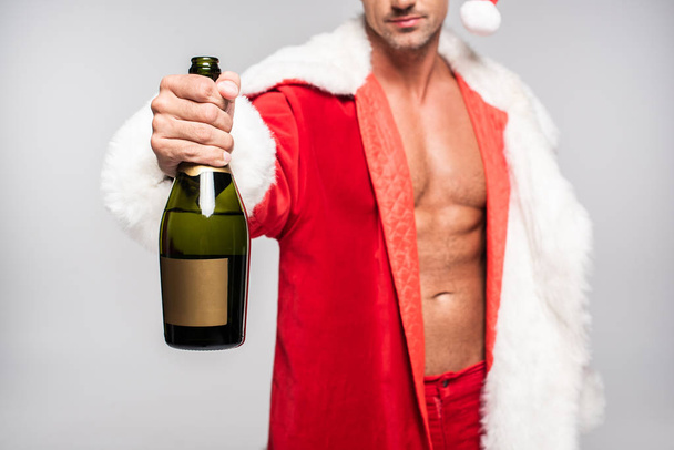 cropped shot of sexy santa holding bottle of champagne with blank label isolated on grey - Photo, Image
