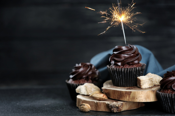 Deliciosos cupcakes com sparkler na mesa escura
 - Foto, Imagem