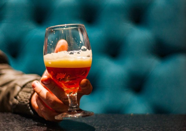 mano de hombre sostiene un vaso de cerveza ámbar Pale Ale en el bar
 - Foto, imagen