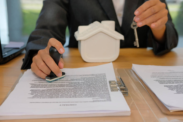 agente imobiliário com chave de casa usando carimbo para carimbar aprovado no documento de contrato de empréstimo hipotecário
 - Foto, Imagem