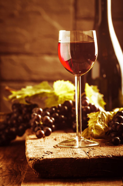 Kırmızı şarap ve üzüm ahşap arka plan üzerinde vintage ortamda - Fotoğraf, Görsel