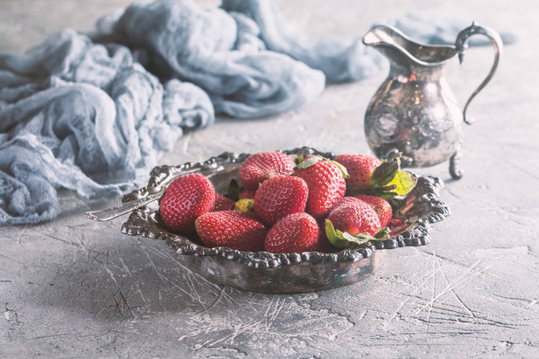 Vintage metal bowl of fresh strawberries with cream on gray background - 写真・画像