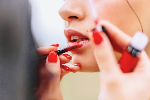 girl paints lips in red on summer street - Fotografie, Obrázek