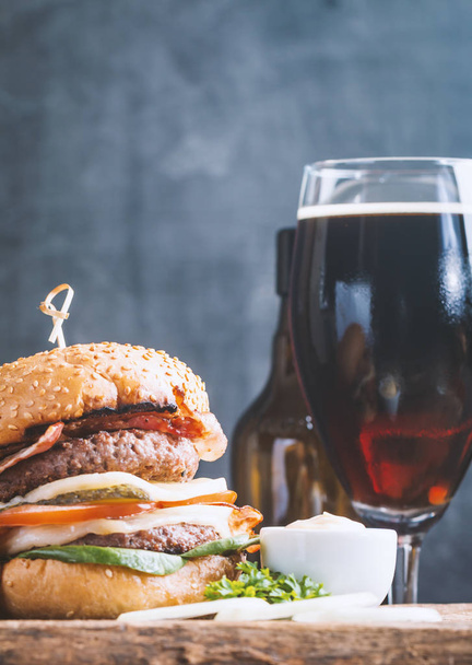 自家製の新鮮なハンバーガーとビンテージ スタイルの木製の背景で黒ビール - 写真・画像