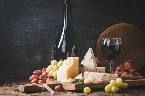 Various types of cheese and red wine still life on wooden table - Fotó, kép