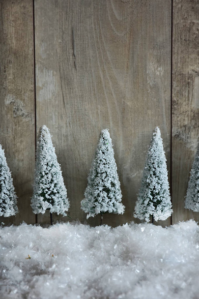 decoration of festive snow-covered Christmas trees on a wooden background. - Photo, Image