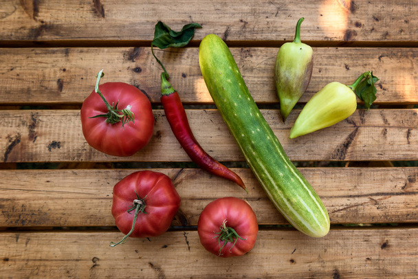Organic Vegetables from a Small Garden on a Rustic Wooden Table - Tomatoes, Cucumber, Paprika, Bell Pepper, Chili Pepper - 写真・画像