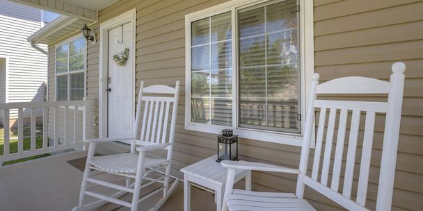 Casa com cadeiras de balanço e mesa na varanda da frente
 - Foto, Imagem