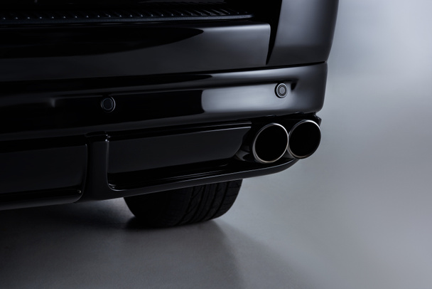 Close-up van zwarte luxeauto op grijze achtergrond - Foto, afbeelding
