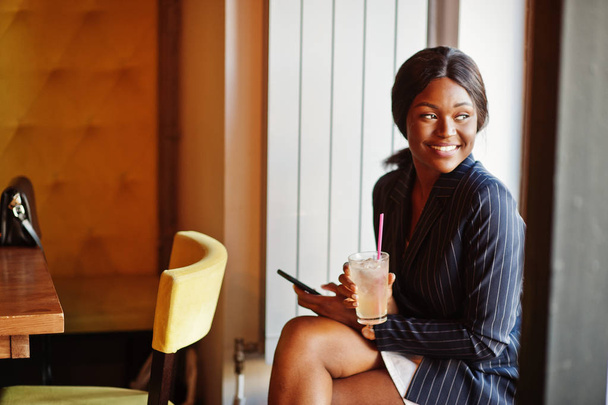 African american businesswoman drinking cocktail lemonade in cafe. Black girl having rest with mobile phone. - Fotografie, Obrázek