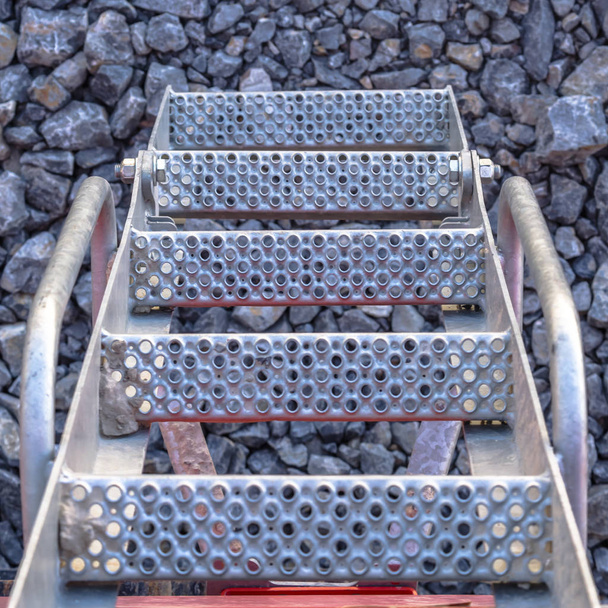 Escaleras metálicas perforadas en un suelo de piedra
 - Foto, imagen