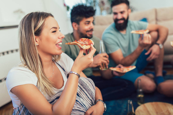 Grupo de jóvenes amigos comiendo pizza.Fiesta en casa.Concepto de comida rápida
. - Foto, Imagen