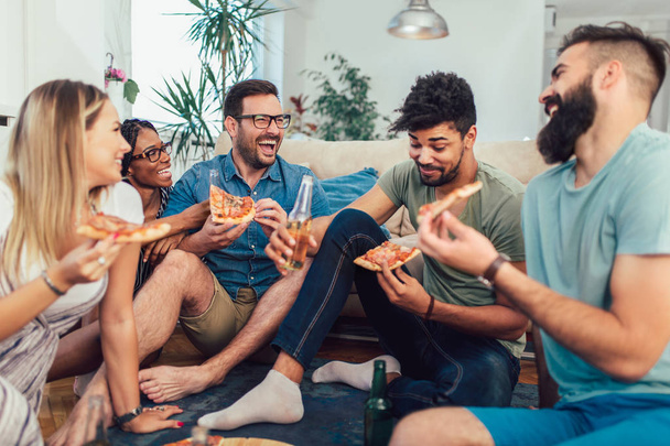 Grupo de jovens amigos comendo pizza.Home partido.
. - Foto, Imagem
