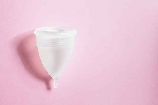 Menstruationstasse auf rosa Hintergrund. alternatives umweltfreundliches feminines Hygieneprodukt, um Blut während des Zeitraums innerhalb der Vagina zu sammeln. Frauengesundheitskonzept - Foto, Bild