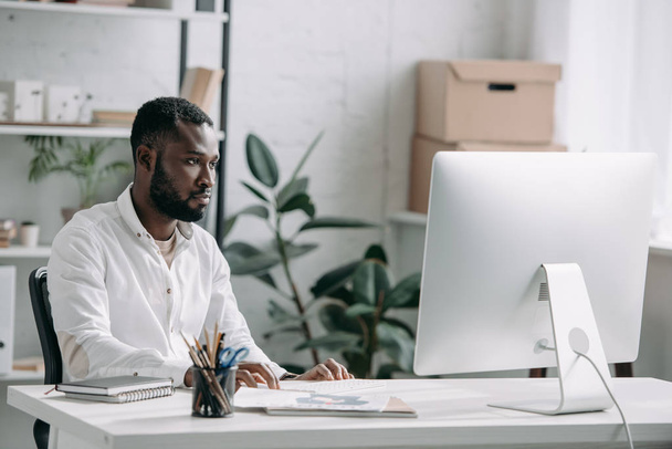 όμορφος Αφρικανικός Αμερικανός επιχειρηματίας που βλέπουν υπολογιστή στο γραφείο - Φωτογραφία, εικόνα
