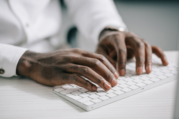 オフィスのコンピューターのキーボードで入力するアフリカ系アメリカ人のビジネスマンの画像をトリミング - 写真・画像
