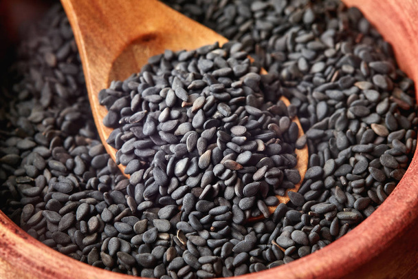 Close up de sementes de gergelim preto em colher de madeira
 - Foto, Imagem