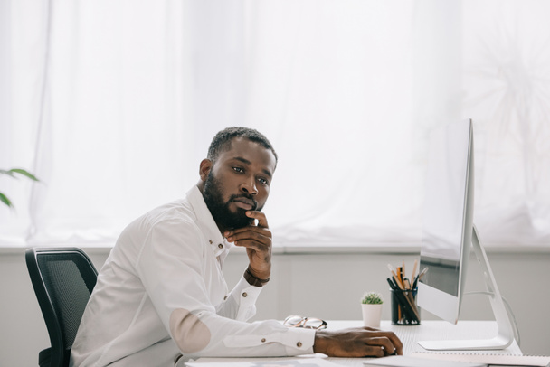 オフィスのコンピューターで働いて、よそ見ハンサムなアフリカ系アメリカ人のビジネスマンの側面図 - 写真・画像