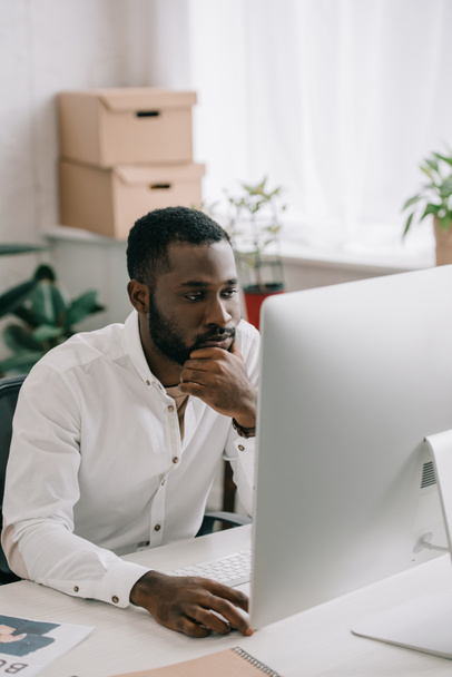 pensive handsome african american businessman working at computer in office - 写真・画像