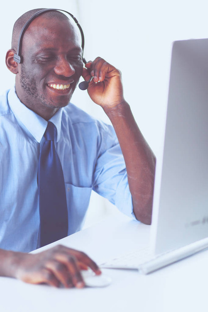 Hombre de negocios afroamericano con auriculares trabajando en su computadora portátil - Foto, imagen