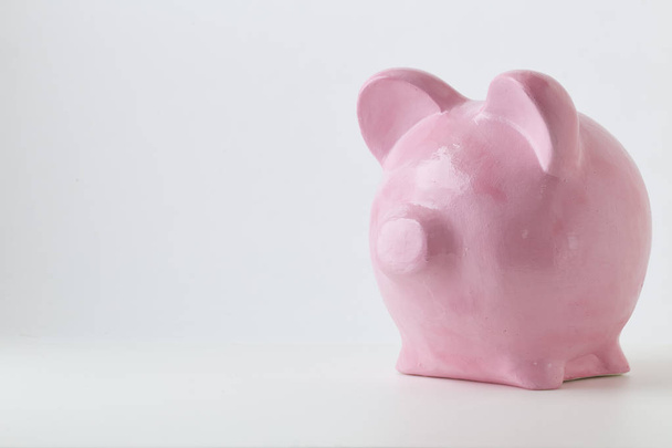 Vaaleanpunainen säästöpossu valkoisella taustalla. Rahoitus, säästää rahaa, luonnollisessa tilassa
 - Valokuva, kuva