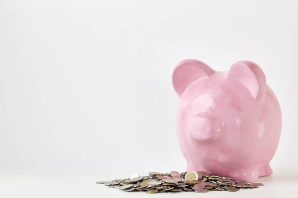 Banco piggy rosa e moedas no fundo branco. Finanças, poupar dinheiro, no estado natural
 - Foto, Imagem