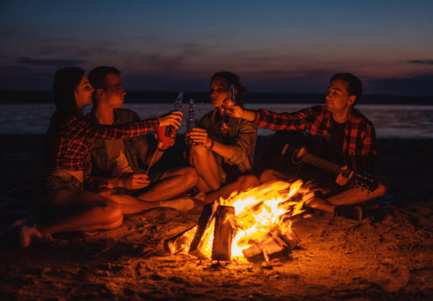 jonge vrienden hebben picnic met vreugdevuur op het strand - Foto, afbeelding